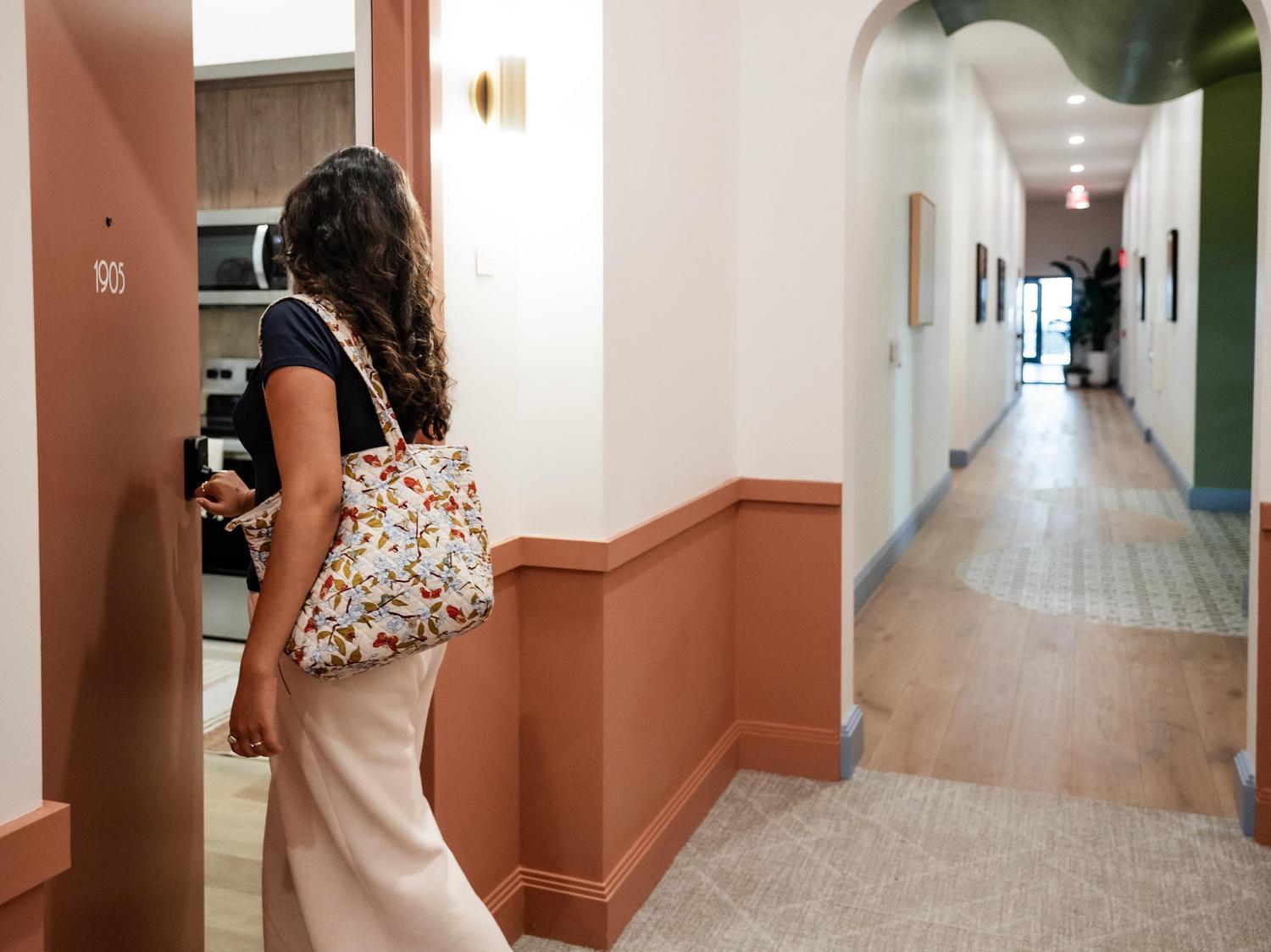 Rambler Atlanta hallway, woman walking through apartment door