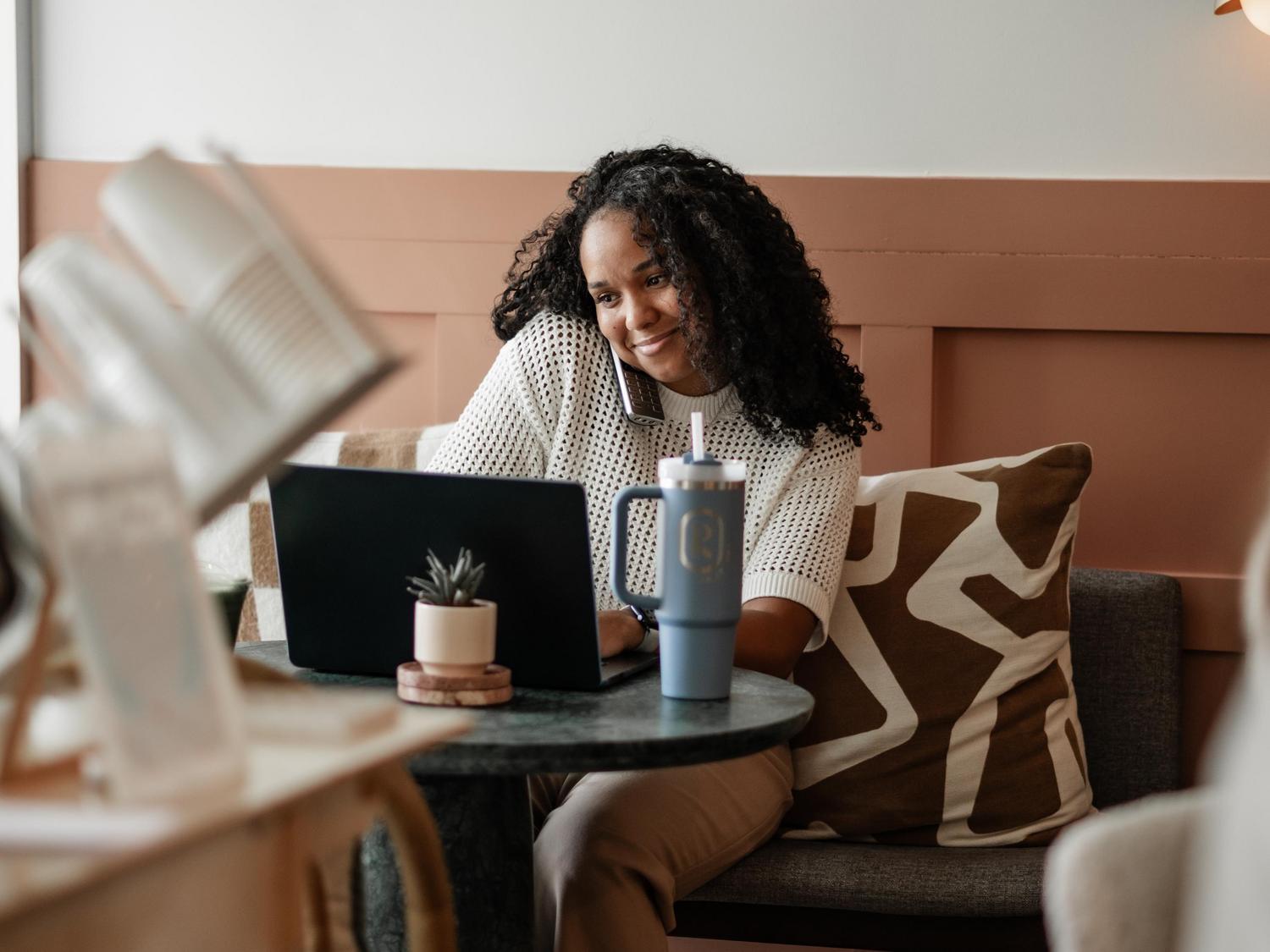 Woman taking a phone call and working on computer in Rambler Atlanta lobby